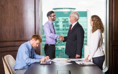 businessmen-shaking-hands-while-another-is-writing