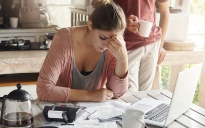 thoughtful-stressed-young-female-sitting-kitchen-table-with-papers-laptop-computer-trying-work-through-pile-bills-frustrated-by-amount-domestic-expenses-while-doing-family-budget